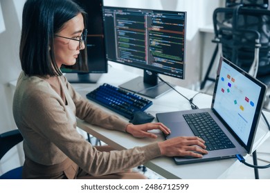Asian prompt engineer develop coding app with software data sitting in front of computer monitor at office