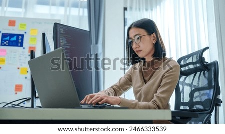 Asian prompt engineer develop coding app with software data sitting in front of computer monitor at office