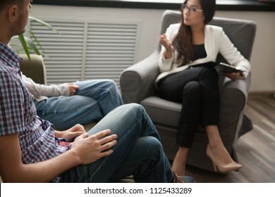 Asian Psychologist Counseling Talking To Unhappy Couple In Office, Family Counselor Sexologist Sitting In Chair Consulting Family During Therapy Session, Marriage And Sexual Problems Solution Concept