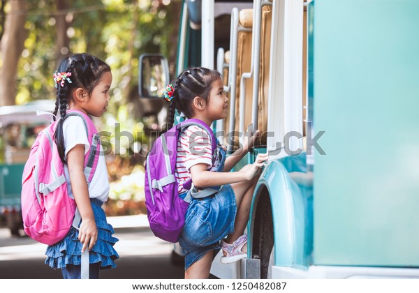 Asian pupil\
kids with backpack holding hand and going to school with school bus\
together. Back to school\
concept.