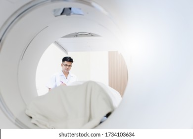 Asian Radiologist Control And Adjust CT Scanner Machine In X-ray Room.Technician Checking Computed Tomography Scanner Machine Or MRI In The Hospital.High Technology Medical Treatment Equipment Concept