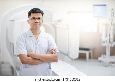 The Asian Radiologist Stands In Front Of The Patient's CT Scanner For Treatment Planning In The Advanced X-ray Technology For Medical Device Concepts.