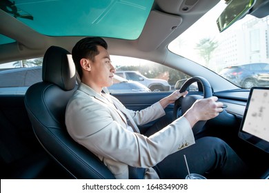 Asian Relaxed Man Is Driving Electric Car