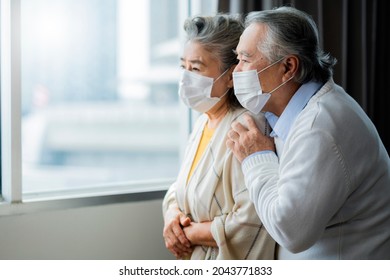 asian retired elderly couple wearing face masks watch the world through their home window hand hug and lonely sadness expression,asian people home isolation social distancing stay home ideas concept - Powered by Shutterstock