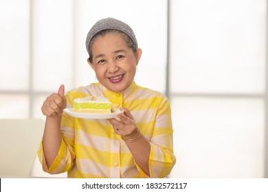 Asian Retired Lady Smiling With Plate Of Cake