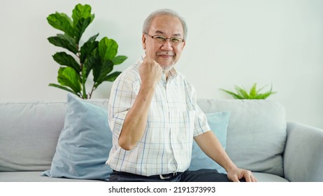 Asian Retired Senior Grandfather Is Sitting On Sofa And Cheering Up Gesture To Encourage Elderly Person Who Has Health Problems. The Elderly Man With Energetic Looking At Camera With Confident Face.