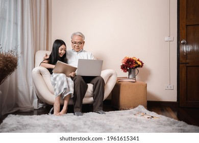 Asian retirement grandfather teaching homework pretty granddaughter by tablet and laptop in the living room. Happy Family educational at home concept. Technology and education. - Powered by Shutterstock