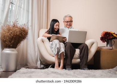 Asian retirement grandfather teaching homework pretty granddaughter by tablet and laptop in the living room. Happy Family educational at home concept. Technology and education. - Powered by Shutterstock