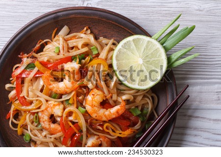 Asian rice noodles with shrimp and vegetables close-up on the table. top view of a horizontal 