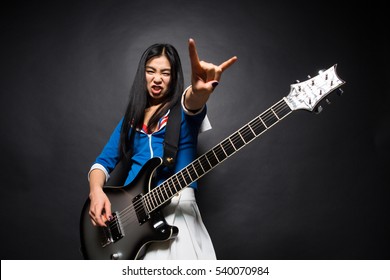 Asian Rock Star Lady Showing Yo Sign While Playing Guitar Isolated On Grey Background In Studio. Rock Music Concept.