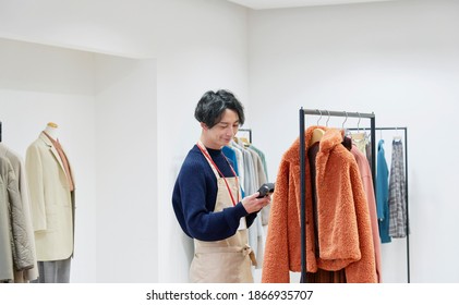 Asian Sales Associate Using The Bar Code Reader