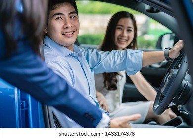 Asian Saleswoman inviting and introducing the couple customer Testing drive in new modern car around showroom, Car service concept - Powered by Shutterstock