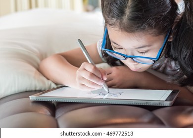 Asian School Child Girl Using Smart  Tablet Device Digital Technology Drawing On Innovative Touchscreen Surface 