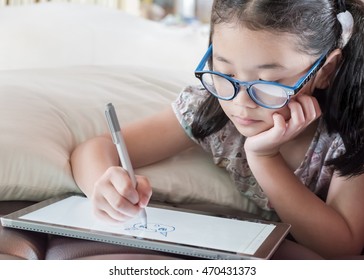 Asian School Child Girl Using Smart  Tablet Device Digital Technology Drawing On Innovative Touchscreen Surface 