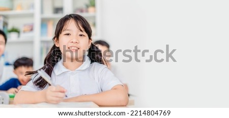 Asian school girl in classroom.school student learning. writing at desk in a classroom at the elementary school. Student girl study doing test in primary school.Children writing notes in the classroom