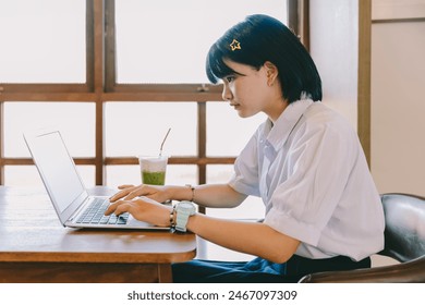 Asian school teenage girl in school uniform concentrate do homework typing laptop computer - Powered by Shutterstock