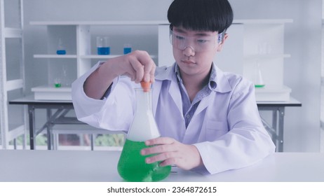 Asian schoolboy doing chemistry experiment in science lab - Shutterstock ID 2364872615