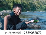 Asian schoolboy holding freshwater algae from diving into the river and pulling it up to study the fertility of the river