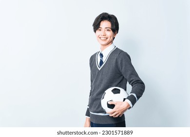 Asian schoolboy holding soccer ball.