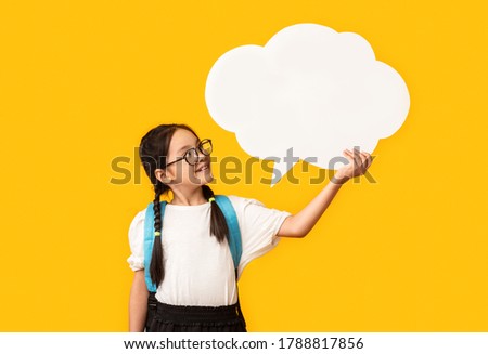 Asian Schoolgirl Holding Blank Speech Bubble Posing Over Yellow Studio Background. Mockup, Free Space