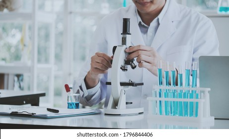 Asian scientist or doctor use microscope  to test for the coronavirus (COVID-19). Or cancer to save people life In lab Or hospital. Successful in researching the treatment of patient