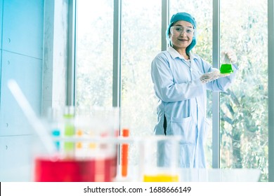 Asian Scientist Pipetting at a Biomedical Laboratory.Focused young life science professional pipetting solution into the glass cuvette. Lens focus