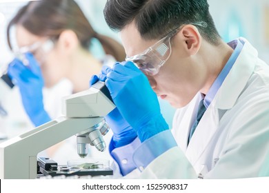 Asian Scientist Team Use Microscope In The Laboratory