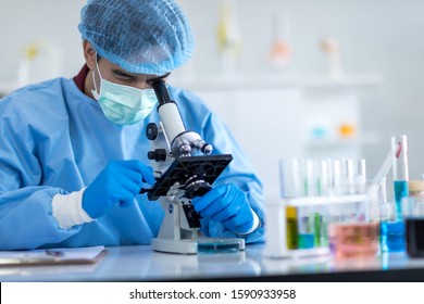 Asian scientists wear protective clothing looking for microscopes while doing medical research in a science laboratory.