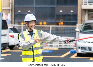 Asian security guard directing traffic on the street. - Shutterstock ID 2232414585