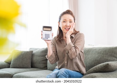 Asian senior age woman having an electronic calculator, trouble