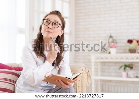 Asian senior age woman who fills out a schedule book,thinks