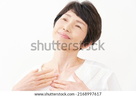 Asian senior aged woman massaging her breasts in white background