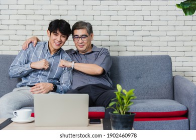 Asian Senior Businessman With Laptop Computer Discuss Together With Young Team In Office. Father Man And His Son Sit On Sofa Talking Chatting On Video Call Conference On Laptop In Living Room At Home