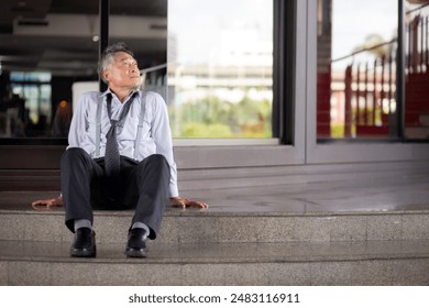 Asian senior businessman sitting on steps thoughtful with stress and frustrated in modern office, elderly business man contemplative to problem with sad and anxious, business and emotion. - Powered by Shutterstock