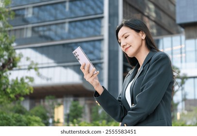 An Asian senior businesswoman Professional woman using smartphone outdoors in urban setting Women in Leadership,ceo - Powered by Shutterstock