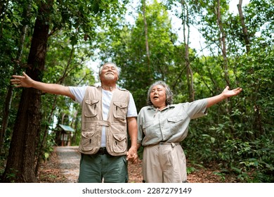 Asian senior couple breathing fresh air during walking together on tropical forest trail. Elderly man and woman enjoy outdoor activity lifestyle travel nature hiking in jungle on summer vacation. - Powered by Shutterstock