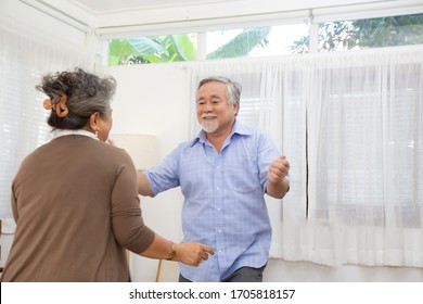 Asian Senior Couple Dancing In The Living Room At Home, Happy Mature Elderly Enjoying A Dance Concept