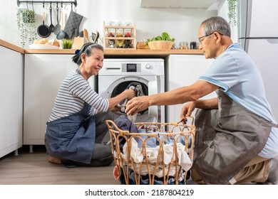 Asian senior couple doing house working and chores in kitchen at home. Active elderly mature grandparents clean and put clothes in washing machine for laundry, enjoy retirement life in house together. - Powered by Shutterstock