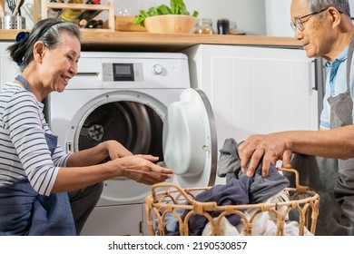 Asian Senior Couple Doing House Working And Chores In Kitchen At Home. Active Elderly Mature Grandparents Clean And Put Clothes In Washing Machine For Laundry, Enjoy Retirement Life In House Together.