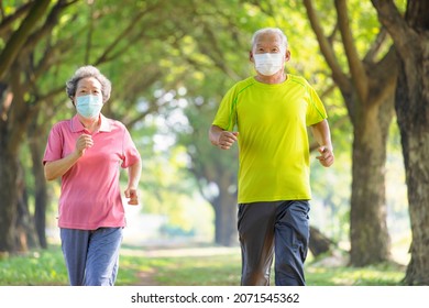 Asian Senior Couple In Face Mask And Jogging In The Park