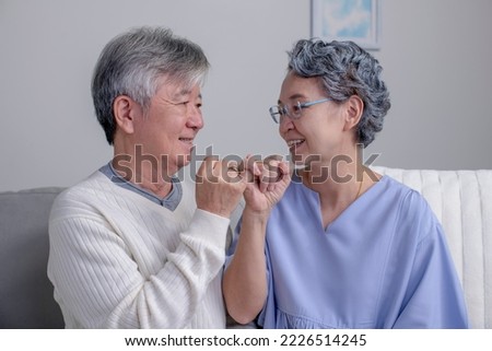 Asian senior couple hands show little finger on sofa in house. Romantic love concept. Hand to pinky swear, pinky promise hand signs.