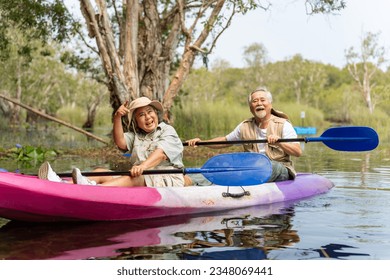 Asian senior couple kayaking together in the lake at mangrove forest on summer vacation. Retired elderly people man and woman have fun outdoor lifestyle travel nature and rowing a boat in the river. - Powered by Shutterstock