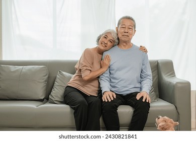 Asian senior couple looking at camera and smiling, senior smiling and looking at tablet Retired people use technology at home Woman hugging man with love Together forever on the sofa at home - Powered by Shutterstock