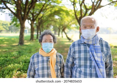 Asian Senior Couple In Medical Mask And Autumn Dress Walking In The Park