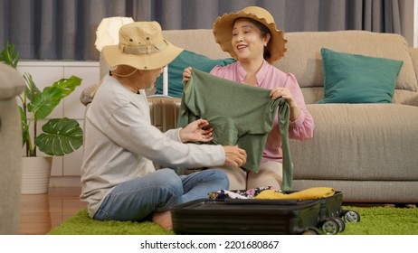 Asian Senior Couple Packing Clothes And Stuff For Travel Trip Together At Home, Senior Retired Couple Enjoying To Arrange Clothes In Living Room, Senior Husband And Wife Organizing Clothes Baggage