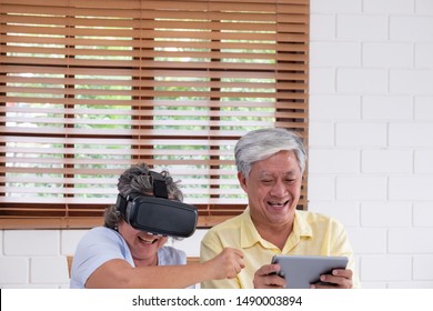 Asian senior couple play virtual realtiy glasses headset and tablet watching vr video and  have fun together in living room at home.senior with technology.aging at home - Powered by Shutterstock