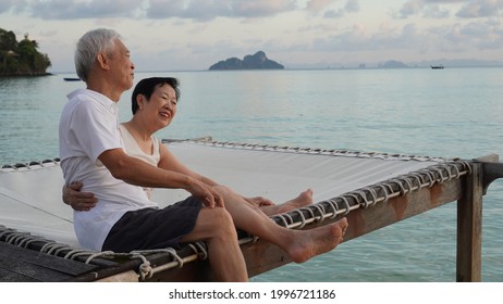 Asian Senior Couple Sitting At Sunrise Sea Early Morning Relaxed Happy Natural Retirement