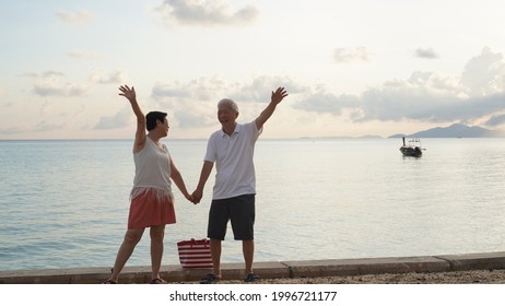 Asian Senior Couple Standing Playing At Beach Sunrise Sea Early Morning Relaxed Happy Natural Retirement