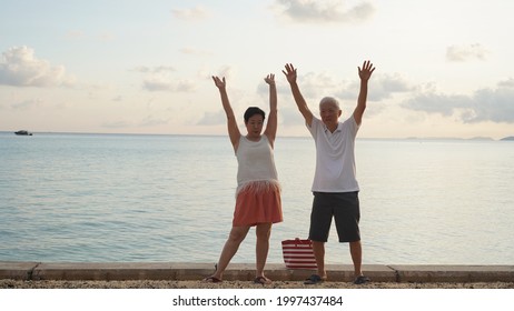 Asian Senior Couple Standing Playing At Beach Sunrise Sea Early Morning Relaxed Happy Natural Retirement