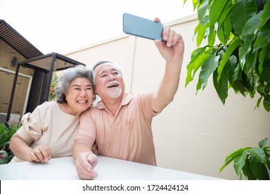 Asian Senior Couple Talking In Video Call Chat On Mobile Phone Or Taking A Selfie, Smart Technology For Old Age And Online Activism Staying Connected Concept